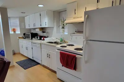 a kitchen with white cabinets and a white refrigerator at Cheerful 2BR suite, onsite free parking CARS or RV in North Vancouver