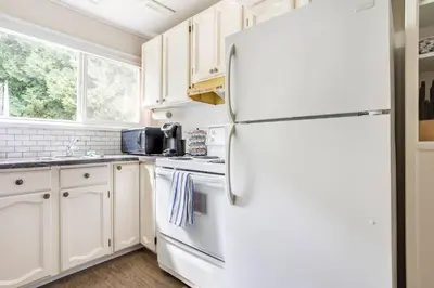 a kitchen with white cabinets and a refrigerator at Quiet Area Near Downtown Walkable To Cafes in Maple Ridge District Municipality