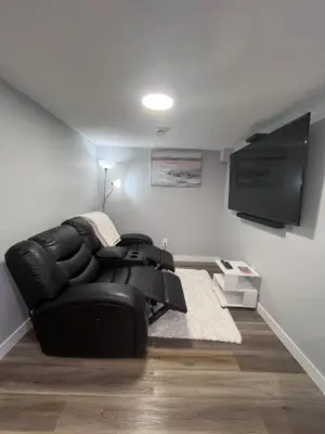 a living room with a black leather couch and a flat screen tv at Adorable Private Suite in Seton SE, Calgary in Calgary