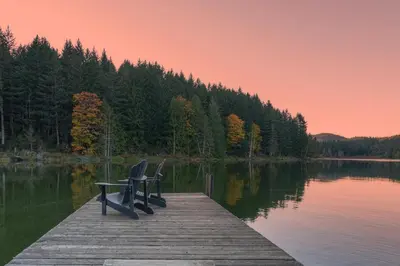 two chairs sitting on a dock on a lake at Cusheon Lake Resort in Ganges