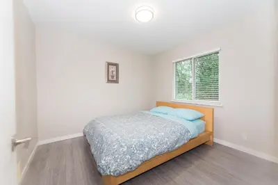 a bedroom with a bed and a window at Burnaby Metrotown 3 bedroom upstairs in Burnaby
