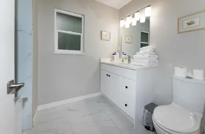 a white bathroom with a toilet and a sink at Burnaby Metrotown 3 bedroom upstairs in Burnaby