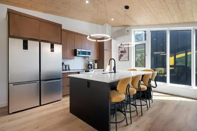 a kitchen with a refrigerator and a table with chairs at Raven's Peak 105 - Ultra luxe Mountain Retreat in Canmore