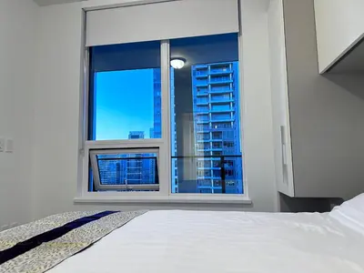 a bedroom with a window with a view of a city at Relocation Special-New condo at Metrotown in Burnaby