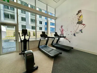 a gym with three treadmills and a painting on the wall at Relocation Special-New condo at Metrotown in Burnaby