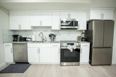 a kitchen with white cabinets and stainless steel appliances at Warm getaway Perfect for 4 in Edmonton