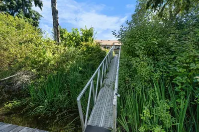 a metal bridge in the middle of a forest at Riverside by Cowichan Lake Cottages in Lake Cowichan
