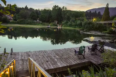 a view of a lake with chairs on a dock at Riverside by Cowichan Lake Cottages in Lake Cowichan