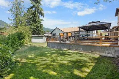 a house with a large yard with a patio at Riverside by Cowichan Lake Cottages in Lake Cowichan