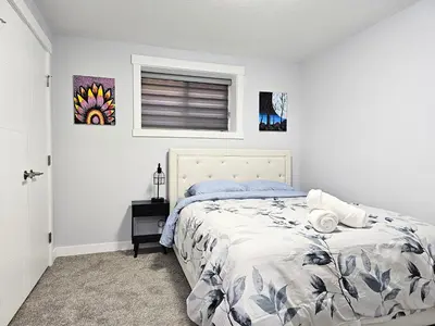 a white bedroom with a bed and a window at Guest Suite in Southeast Calgary in Calgary