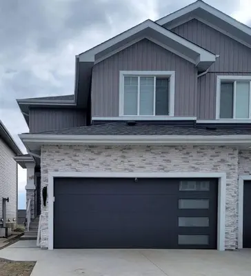 a house with a black garage door in front of it at Guest Suite in SouthWest Edmonton in Edmonton