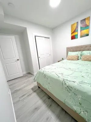 a white bedroom with a bed and a door at Guest Suite in SouthWest Edmonton in Edmonton