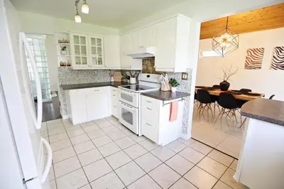 a kitchen with white cabinets and a dining room with a table at Family Pet Friendly AC Disney Near WEM in Edmonton
