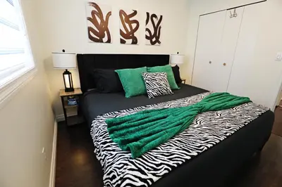 a bedroom with a bed with a green blanket on it at Family Pet Friendly AC Disney Near WEM in Edmonton