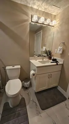 a bathroom with a toilet and a sink and a mirror at Luxury Basement Suite with 2 Bedrooms, 2 Queen Beds, Free Wi-Fi, and Free Parking in Calgary