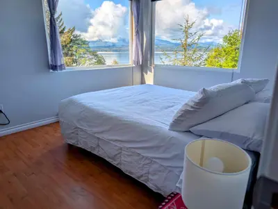 a bedroom with a bed and a large window at Cliff Haven on the Bay in Alert Bay