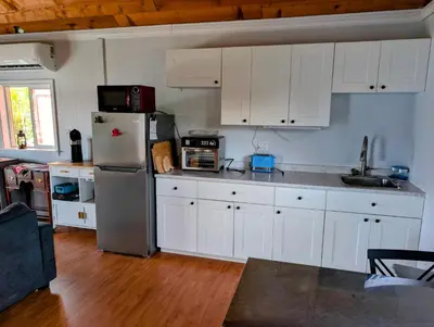 a kitchen with white cabinets and a stainless steel refrigerator at Cliff Haven on the Bay in Alert Bay