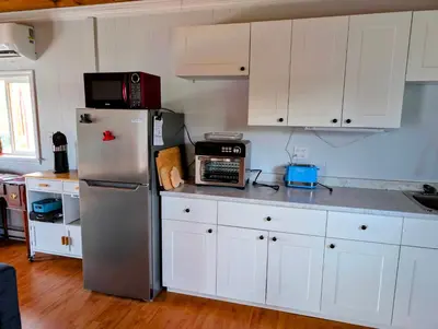 a kitchen with white cabinets and a stainless steel refrigerator at Cliff Haven on the Bay in Alert Bay