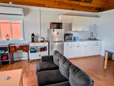 a living room with a couch and a kitchen at Cliff Haven on the Bay in Alert Bay