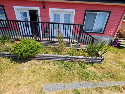 a red house with a flower garden in front of it at Gordie's Inn & Suites in Alert Bay