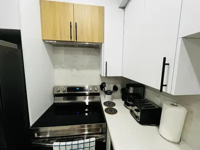 a kitchen with white cabinets and a stove top oven at Amy's 2-Bedroom Residence in Calgary