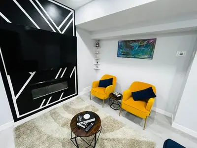 a living room with two yellow chairs and a large tv at Amy's 2-Bedroom Residence in Calgary
