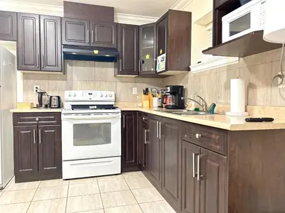 a kitchen with wooden cabinets and a white stove top oven at Near Skytrain Metrotown Private Entry 3min walk to grocery food in Burnaby
