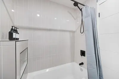 a white bathroom with a shower and a sink at Flora's House in Calgary