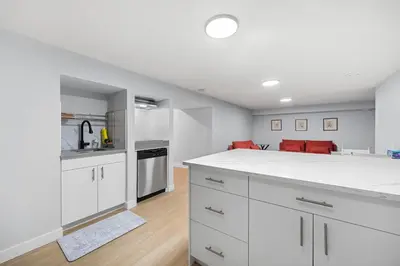 an empty kitchen with white cabinets and red chairs at Flora's House in Calgary