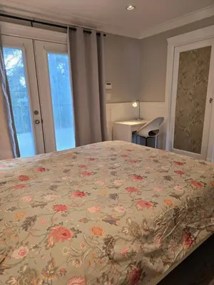 a bedroom with a large bed with a floral bedspread at Cozy home in Brookswood in Langley
