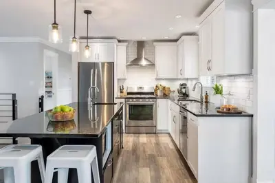 a kitchen with white cabinets and a black counter top at Cozy home in Brookswood in Langley