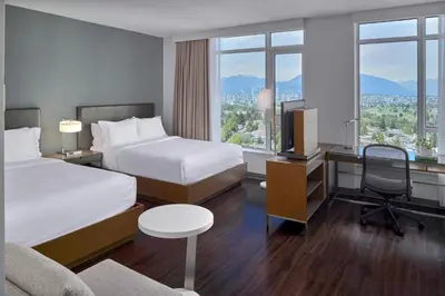 a hotel room with two beds and a desk with a television at Element by Westin Vancouver Metrotown in Burnaby