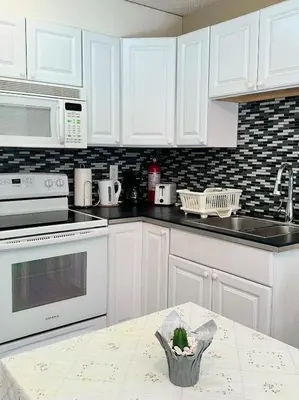 a kitchen with white cabinets and a table with a plant at Capilano Happylife in North Vancouver