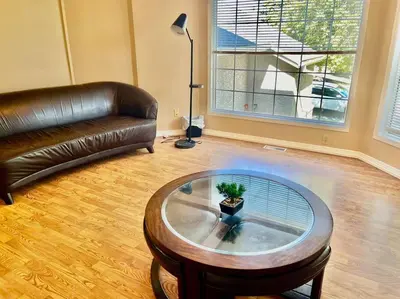 a living room with a leather couch and a coffee table at Airport 4BR2BA Mainfloor Suite 1min walk to bus stop in Calgary