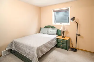 a bedroom with a bed and a lamp and a window at Airport 4BR2BA Mainfloor Suite 1min walk to bus stop in Calgary