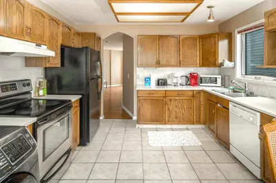 a kitchen with wooden cabinets and stainless steel appliances at Airport 4BR2BA Mainfloor Suite 1min walk to bus stop in Calgary