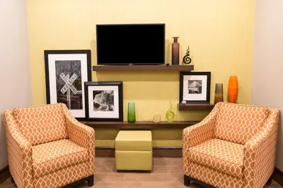 a living room with two chairs and a tv at Hampton Inn by Hilton Lloydminster in Lloydminster