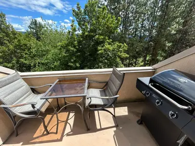 a patio with two chairs and a table and a grill at Borgata Lodge Resort in Kelowna