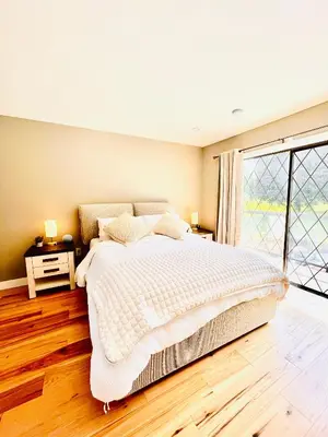 a bedroom with a large bed and a large window at Oceanside Manor - Fancy Room - Golf course & Beach View in Qualicum Beach