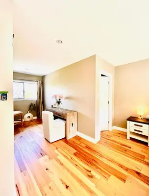 an empty living room with a wooden floor and a desk at Oceanside Manor - Fancy Room - Golf course & Beach View in Qualicum Beach