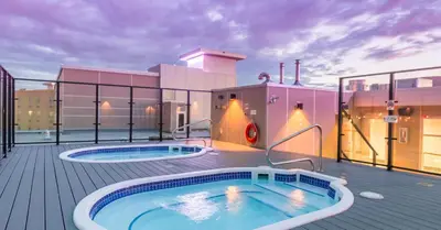 a hot tub on a deck with a building at Hotel Clique Calgary Airport in Calgary