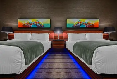 two beds in a room with two monitors on the wall at Hotel Clique Calgary Airport in Calgary