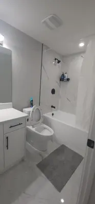 a white bathroom with a toilet and a bath tub at fabulous and cozy guest suite in Calgary