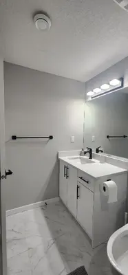a white bathroom with a sink and a mirror at fabulous and cozy guest suite in Calgary