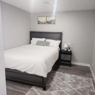 a bedroom with a large bed with white sheets at fabulous and cozy guest suite in Calgary