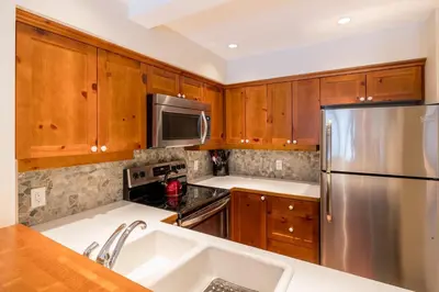 a kitchen with wooden cabinets and a stainless steel refrigerator at #24 Treeline in Whistler