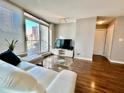a living room with a white couch and a tv at Modern spacious Apt plus Solarium and Den in Downtown Vancouver with Parking and Pool in Vancouver