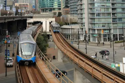 two trains on tracks in a city with buildings at Modern spacious Apt plus Solarium and Den in Downtown Vancouver with Parking and Pool in Vancouver