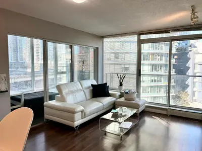 a living room with a white couch and large windows at Modern spacious Apt plus Solarium and Den in Downtown Vancouver with Parking and Pool in Vancouver