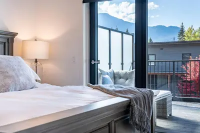 a bedroom with a bed and a large window at Base Camp Revy! in Revelstoke